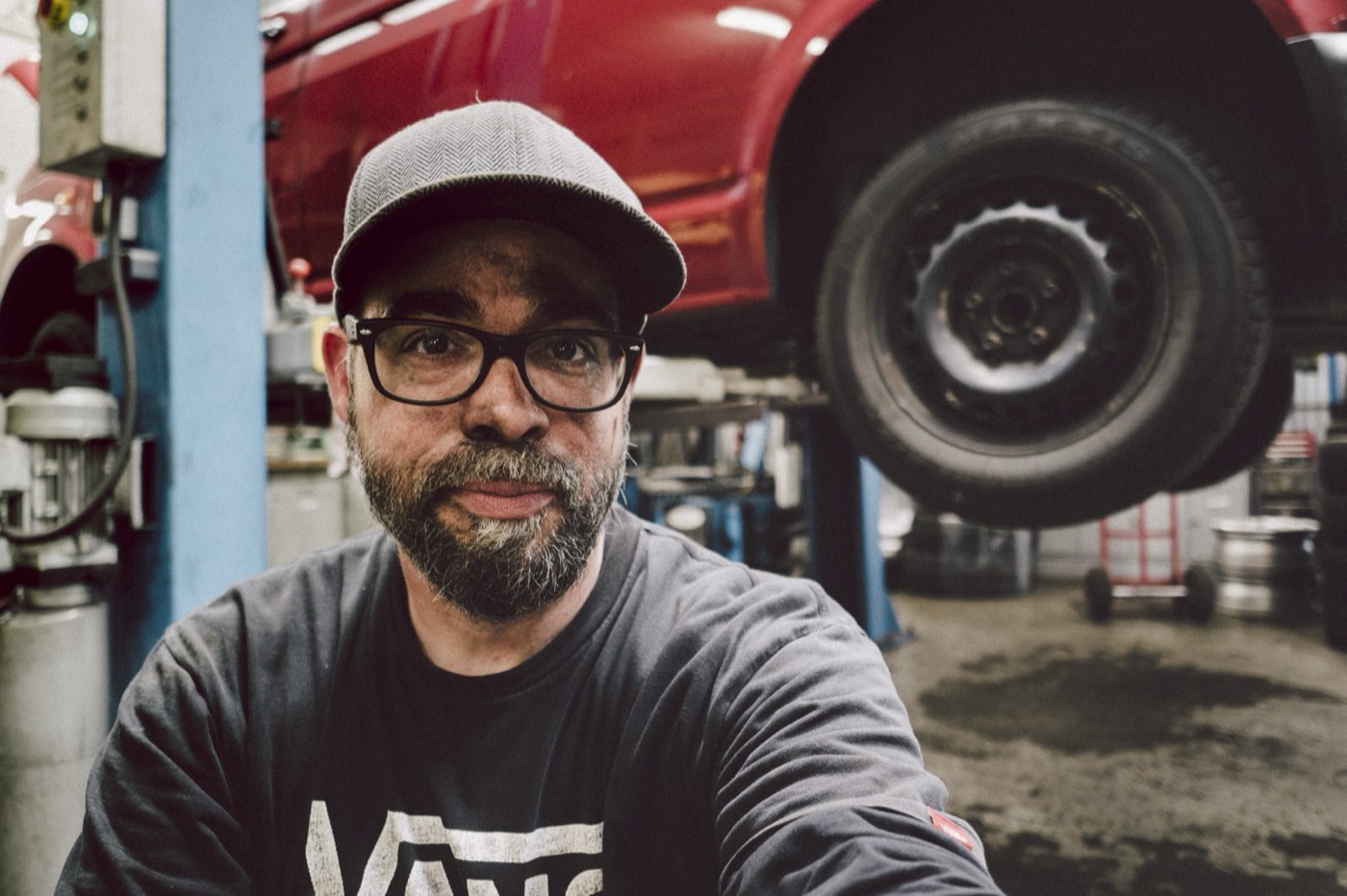 Steven in der Werkstatt vor dem aufgebockten VW T5 beim Bremsenwechsel
