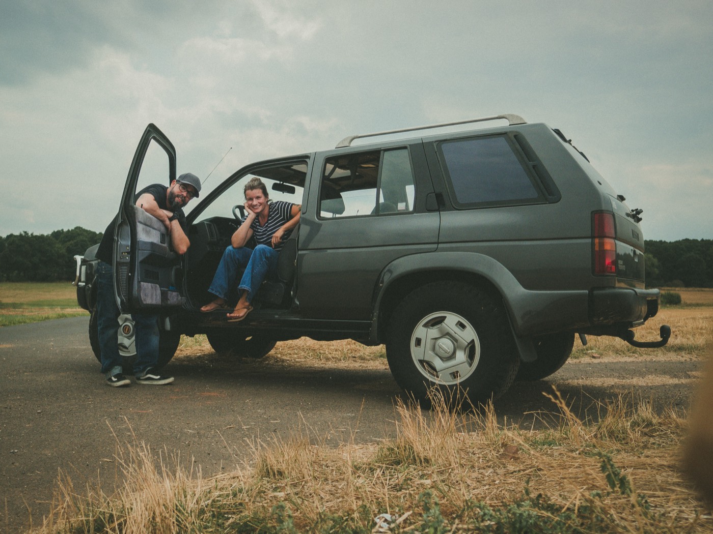 Maria und Steven mit dem Nissan Terrano I Juno auf einem Feldweg — unser Abenteuermobil vor dem VW T5